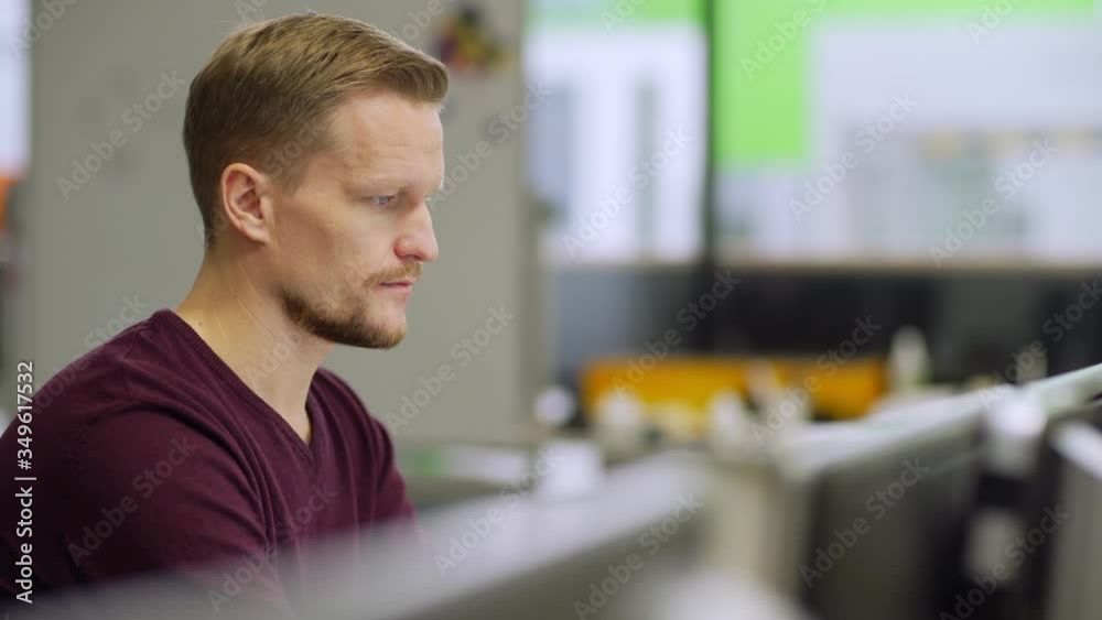 Tracking side view shot of focused middle aged engineer working on computer sitting at desk in laboratory