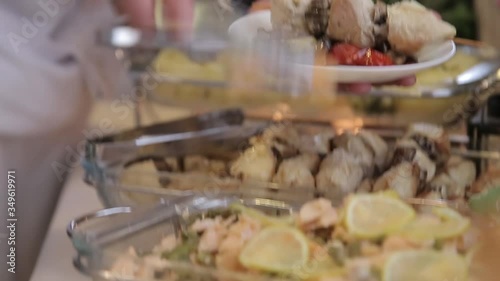 Close up view human hands putting on plate snacks at stand up wedding buffet.  Catering in the proccess.