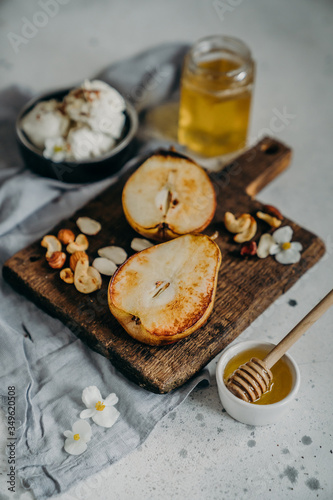 Baked Pears With Honey, Walnuts, Almond microgreens And flowers on a wooden board with Ricotta curd soft cheese