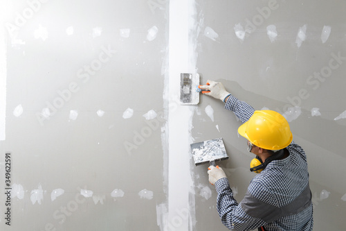 interior decoration construction furniture builtin.Plasterer in working uniform plastering the wall indoors.