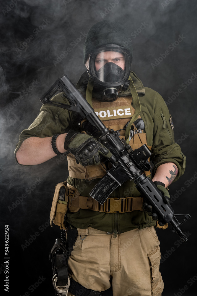 Police officer in gas mask with assault rifle. Uniform conforms to elite task force of the United States. Shot in studio.
