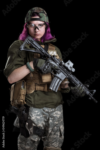 Female police officer with pink hair. Uniform conforms to elite task force of the United States. Shot in studio. Isolated with clipping path. © maximapryatin
