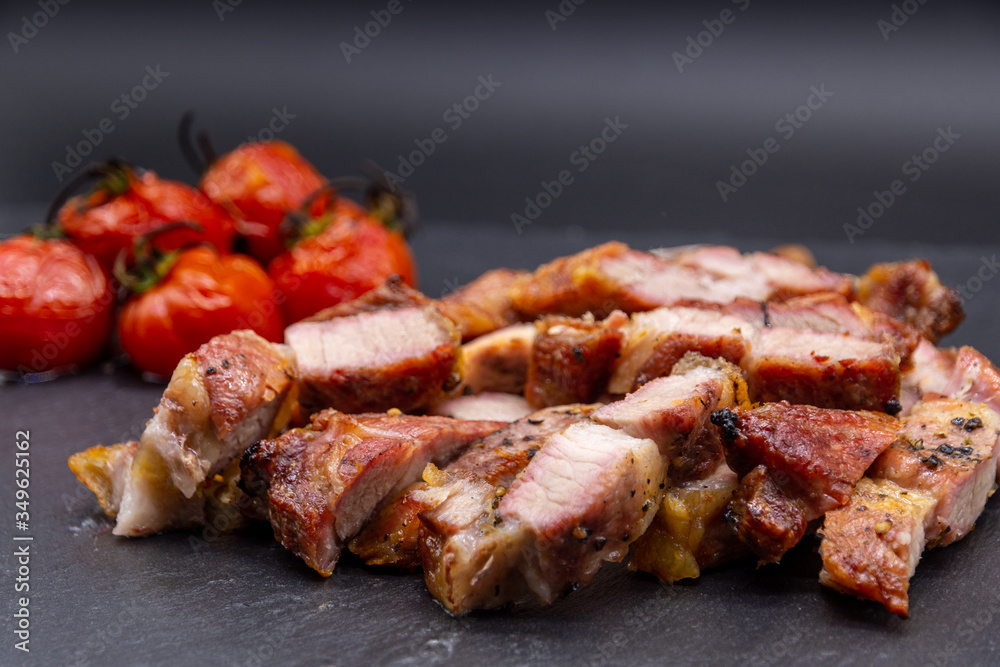 pork steak on black slate and grilled tomatoes and salt
