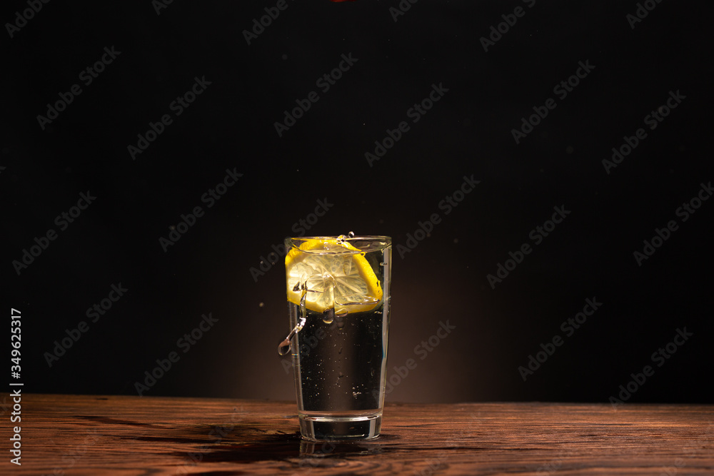 lemon in glass of water on black background