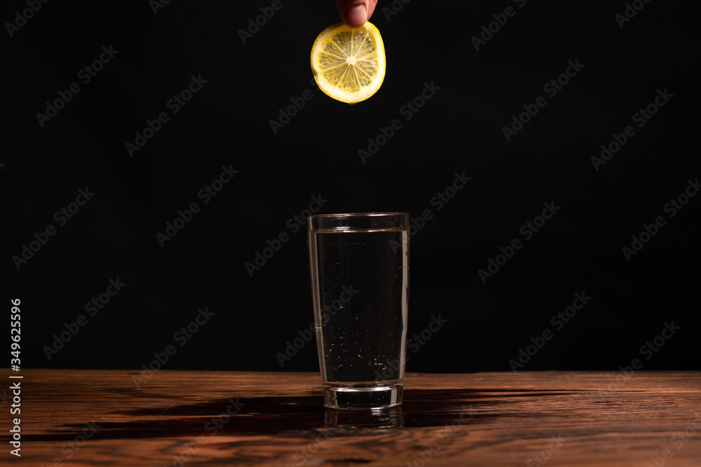 lemon in glass of water on black background