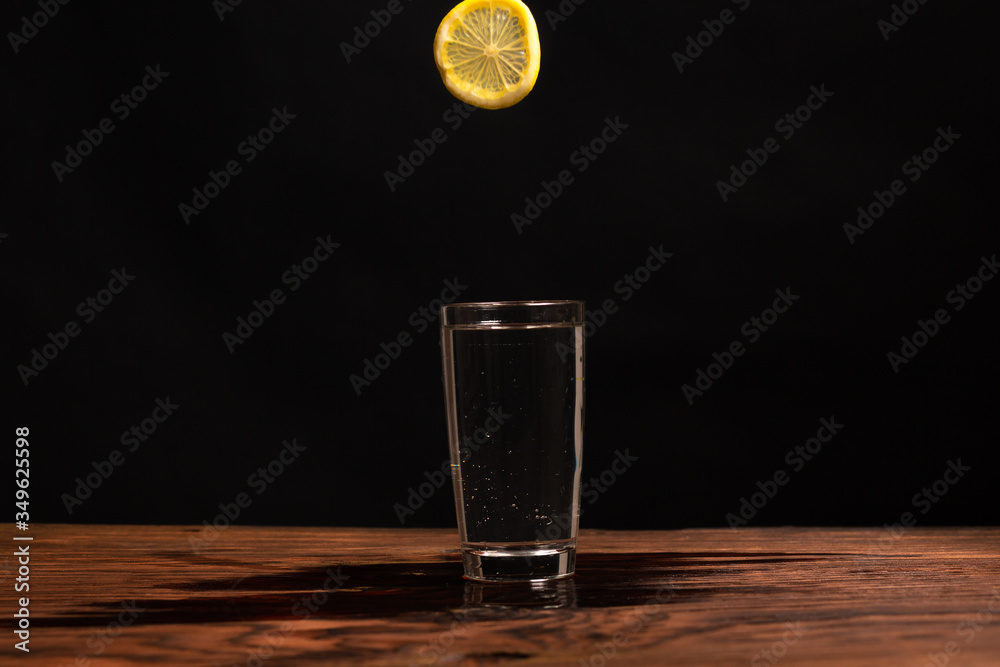 lemon in glass of water on black background