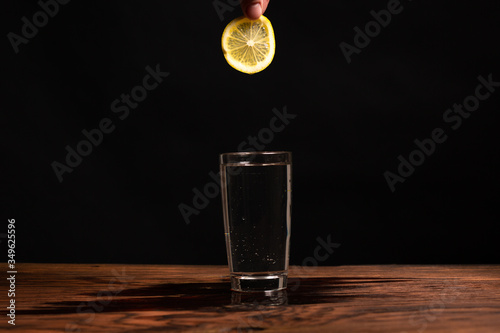 Obraz na płótnie lemon in glass of water on black background w salonie