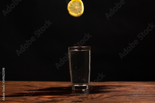 lemon in glass of water on black background