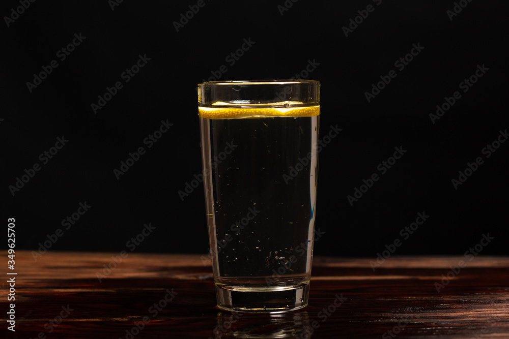 lemon in glass of water on black background