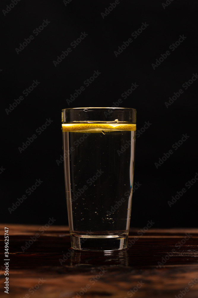 lemon in glass of water on black background