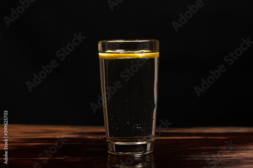 lemon in glass of water on black background