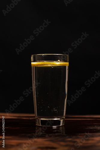 Obraz na płótnie lemon in glass of water on black background w salonie
