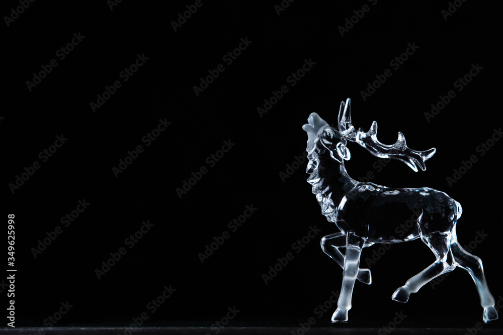 Fototapeta premium Glass figurine of a deer on a black background 