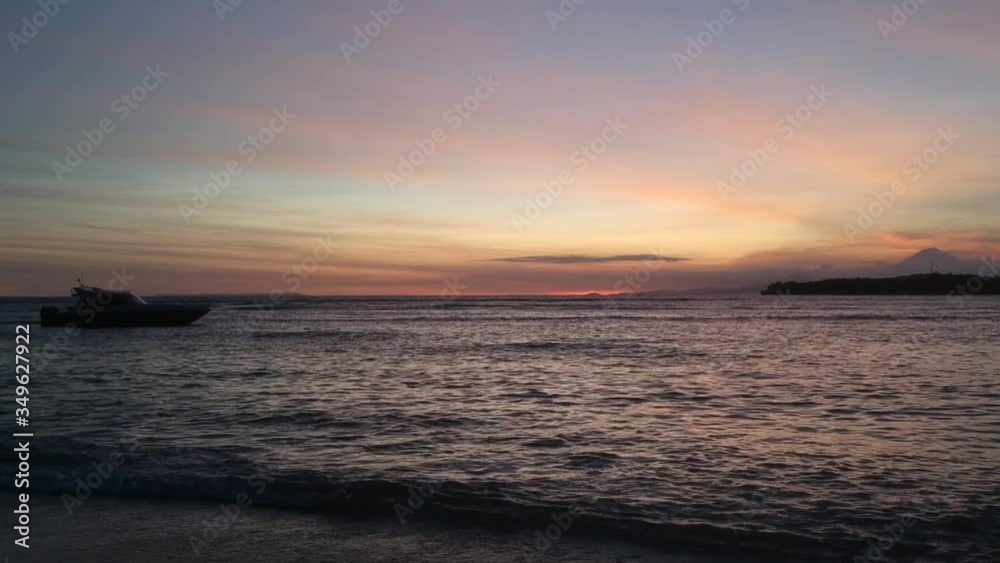 boat sailing in front of a colorful sunset with a volcano on the background boat sailing in front of a colorful sunset with a volcano on the background