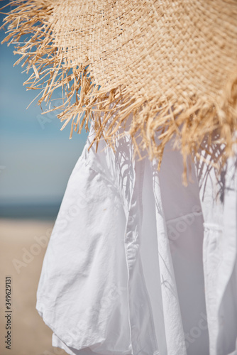 Straw hat, white blouse on a beach