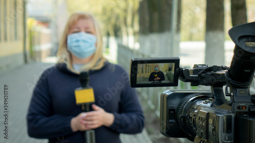 Photography A female journalist in a protective medical mask is reporting in a deserted city