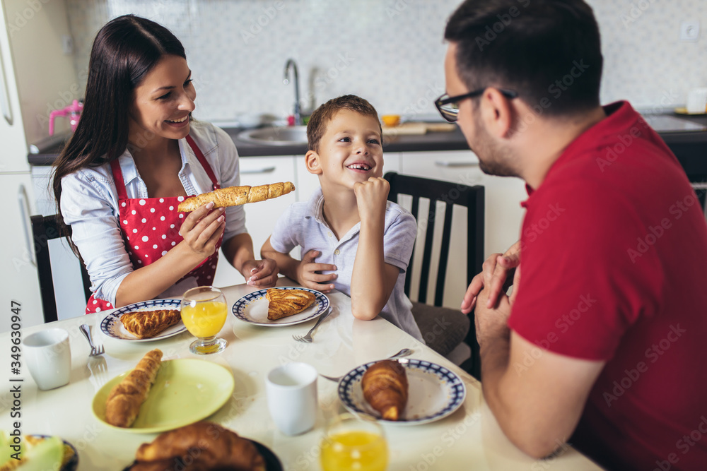 Happy mother, father and son having breakfast at home