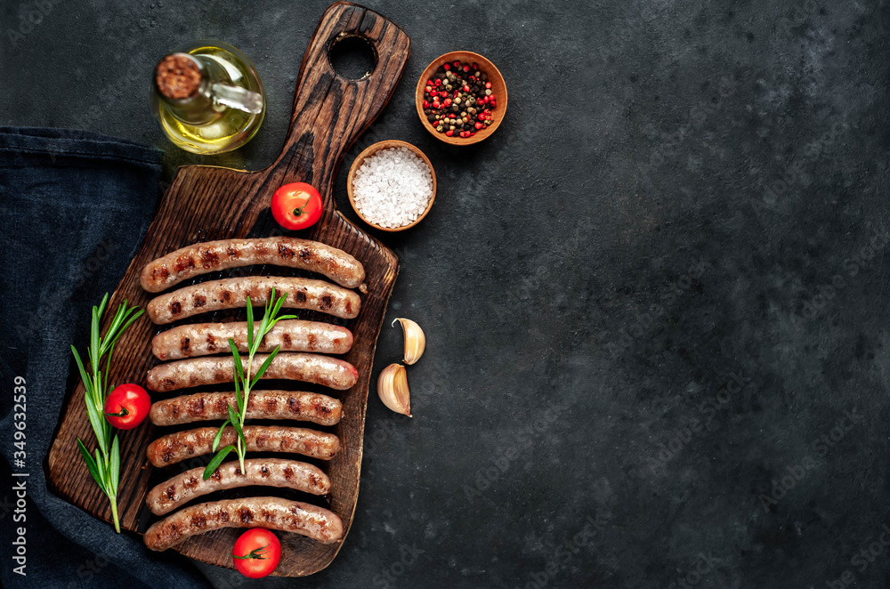 grilled sausages with ingredients on a cutting board on a stone background with copy space for your text