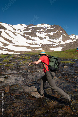 Montañero vadeando el cauce de la laguna Hondera en la Cañada de Siete Lagunas, en el Parque Nacional de Sierra Nevada en el ascenso al pico Mulhacén (3479 m).