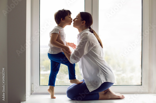 mom and son are sitting in a white shirt and a T-shirt on the window of a house