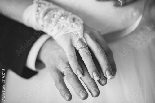 Monochrome image of hands of the groom and bride and their wedding rings. Vintage film grain filter style