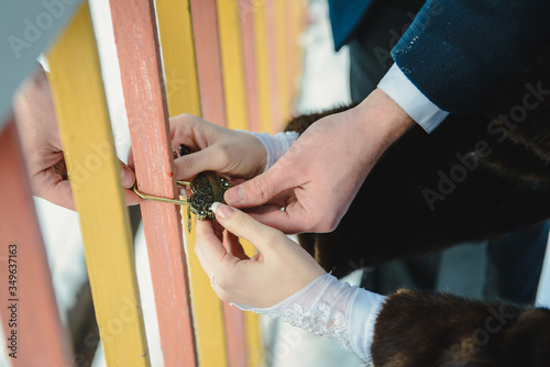 Hands of groom and bride. Bride and groom hang up a wedding padlock on a bridge. Wedding tradition to hang up a lock 