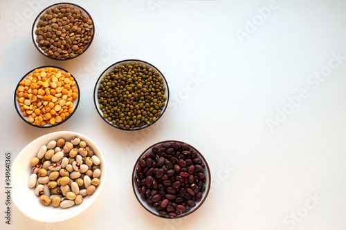 Different types of legumes in bowls on a white background