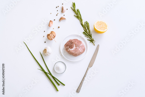 The concept of cooking meat with spices. Raw pork meat, onion, rosemary, garlic, chili pepper on a light background top view.