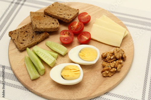 boiled egg, cut in half, cucumber wedges, cheese wedges, toast, healthy food on a breakfast board