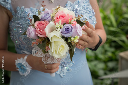 bride holds a delicate artificial bouquet of flowers