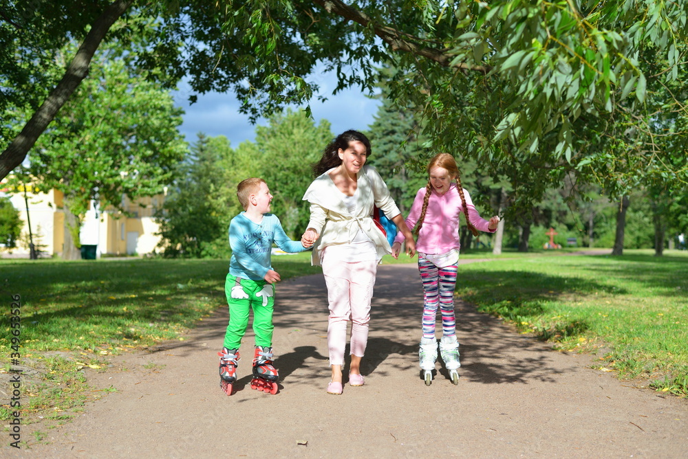 Woman rolls children's hands on roller skates in the Park in the summer in St. Petersburg Woman rolls children's hands on roller skates in the Park in the summer in St. Petersburg
