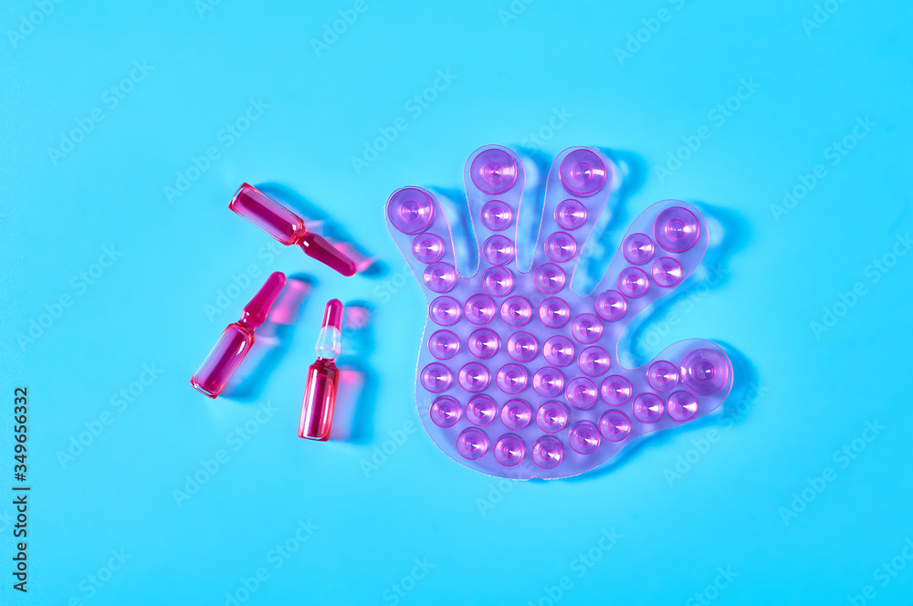 One rubber toy human palm with many suction cups near red vaccine on blue background. Healthcare concept