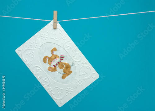 Handmade cross-stitch postcard hanging on a rope with clothespin. Bunny, rabbit.