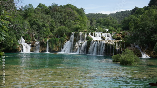 some beautiful waterfalls surrounded by forests of green trees under a blue sky