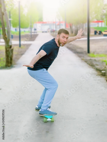 a bearded middle aged guy rides a skateboard in a city Park