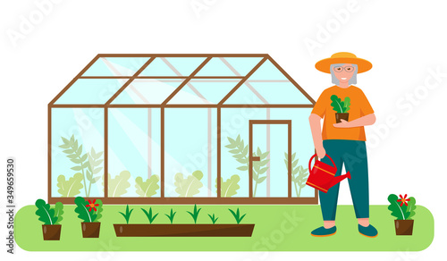 Elderly woman near greenhouse in the garden.