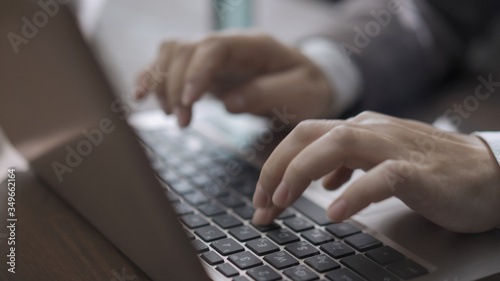 Female hands typing on laptop keyboard. Super close up of businesswoman's hands working computer, woman in suit sits at wooden office table