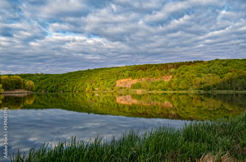 Landscape of a forest lake on a background of cloudy sky.