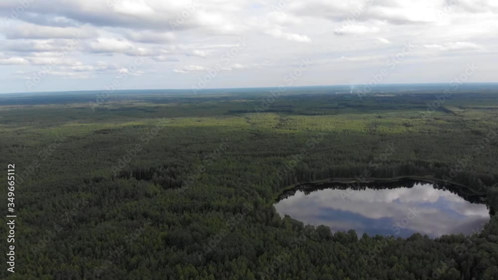 Aerial drone shot over a beautiful forest lake. The sky is reflected in the lake Aerial drone shot over a beautiful forest lake. The sky is reflected in the lake