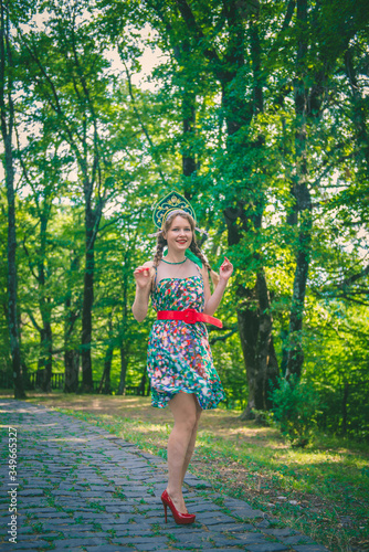 A young woman in a colored dress with a red belt and red shoes with a cocoanut on her head © Ekaterina Voitenkova