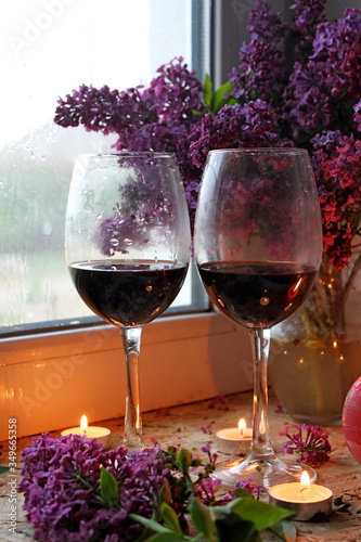 still life with lilac flowers in glass vase. still life with flowers and wine. Still life with lilac and wine. Romantic atmosphere. lilac bouquet. Candles and red wine