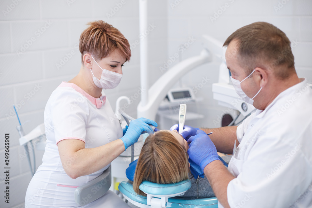 Obraz premium Doctor dentist treats teeth of a beautiful young girl patient.