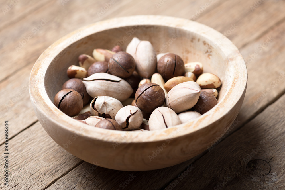 Dried mixed nuts in wooden bowl closeup. Macadamia, Pecan and Brazil nuts with knife on wooden table. Studio macro shoot. Dried mixed nuts in wooden bowl closeup. Macadamia, Pecan and Brazil nuts with knife on wooden table. Studio macro shoot.