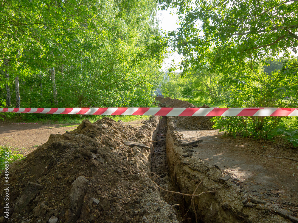 Protective tape due to land work. Digging up ditches to prevent forest fires. Land management of modern park territories. Protective tape due to land work. Digging up ditches to prevent forest fires. Land management of modern park territories.