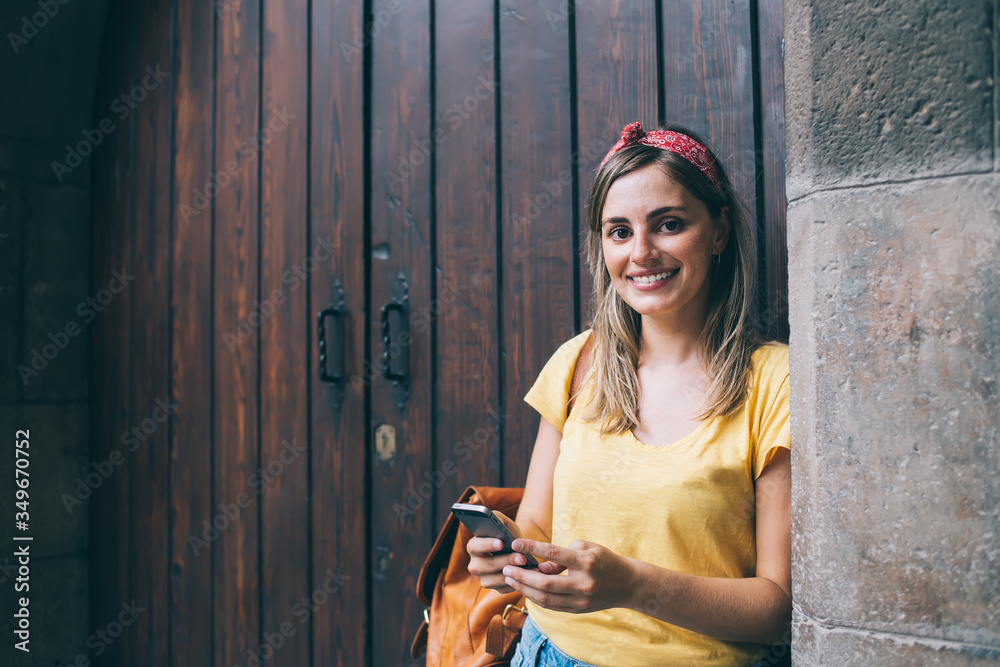 Obraz premium Smiling traveling woman using smartphone on street