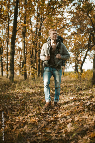Urban dweller in the wild. Backpacker walking in autumn forest. Caucasian young man tourist with a big backpack hikes in the autumn forest © Svyatoslav Lypynskyy