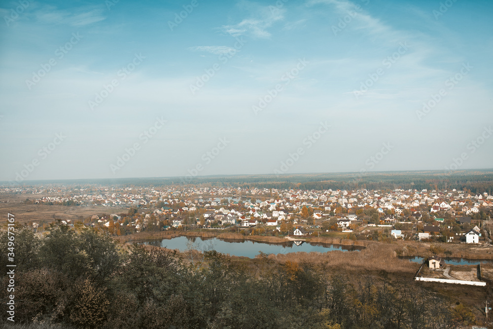 Modern cottage town or urban-type village on the lake. Rural panoramic landscape against the blue sky. Shot from the mountain. High angle view