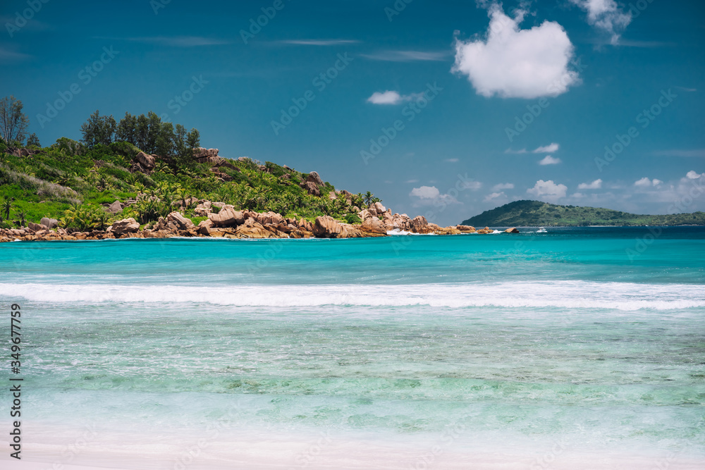 Blue lagoon and white wave at Anse Cocos beach, La Digue island, Seychelles. Luxury vacation travel destination