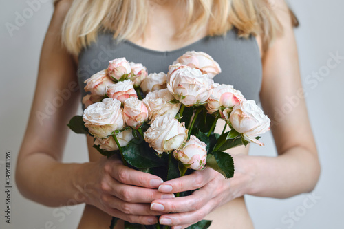 White-pink roses in the hands of a happy woman. Rose petal close-up. Beautiful holiday spring bouquet. Florist girl with blossom flower. Fresh floral bunch. Romantic surprise from a loved one
