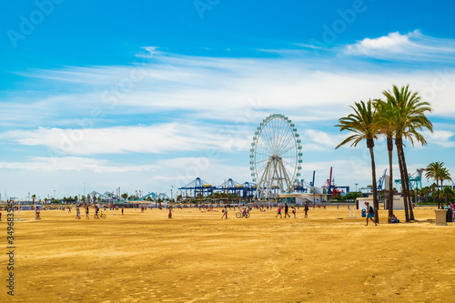 Tourists and locals go to the beach, with the Ferris wheel in the background